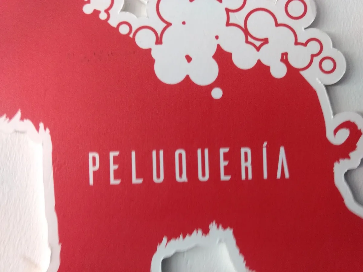 Cartel rojo de la peluquería, con la palabra Peluquería en letras blancas